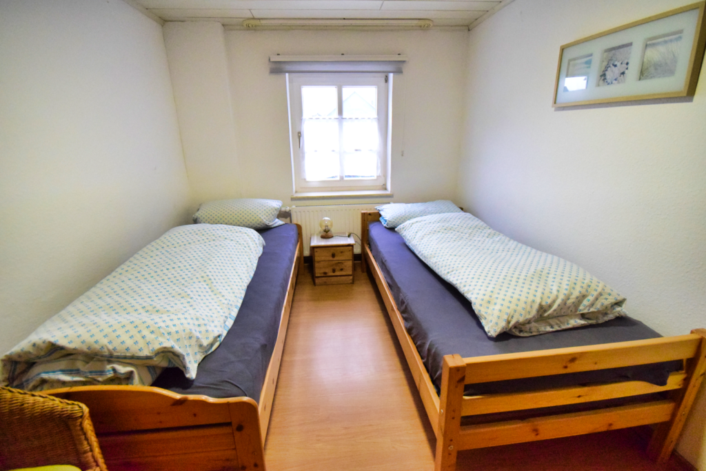 Sie sehen zwei Einzelbetten in einem Monteurzimmer, die Betten sind aus Kieferholz, sauber und gepflegt.